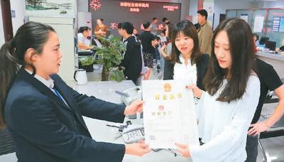 河北省承德市網(wǎng)絡(luò)代購經(jīng)營者陳晨(右)從工作人員手中接過帶有統(tǒng)一社會信用代碼的營業(yè)執(zhí)照。 劉環(huán)宇攝(人民圖片)