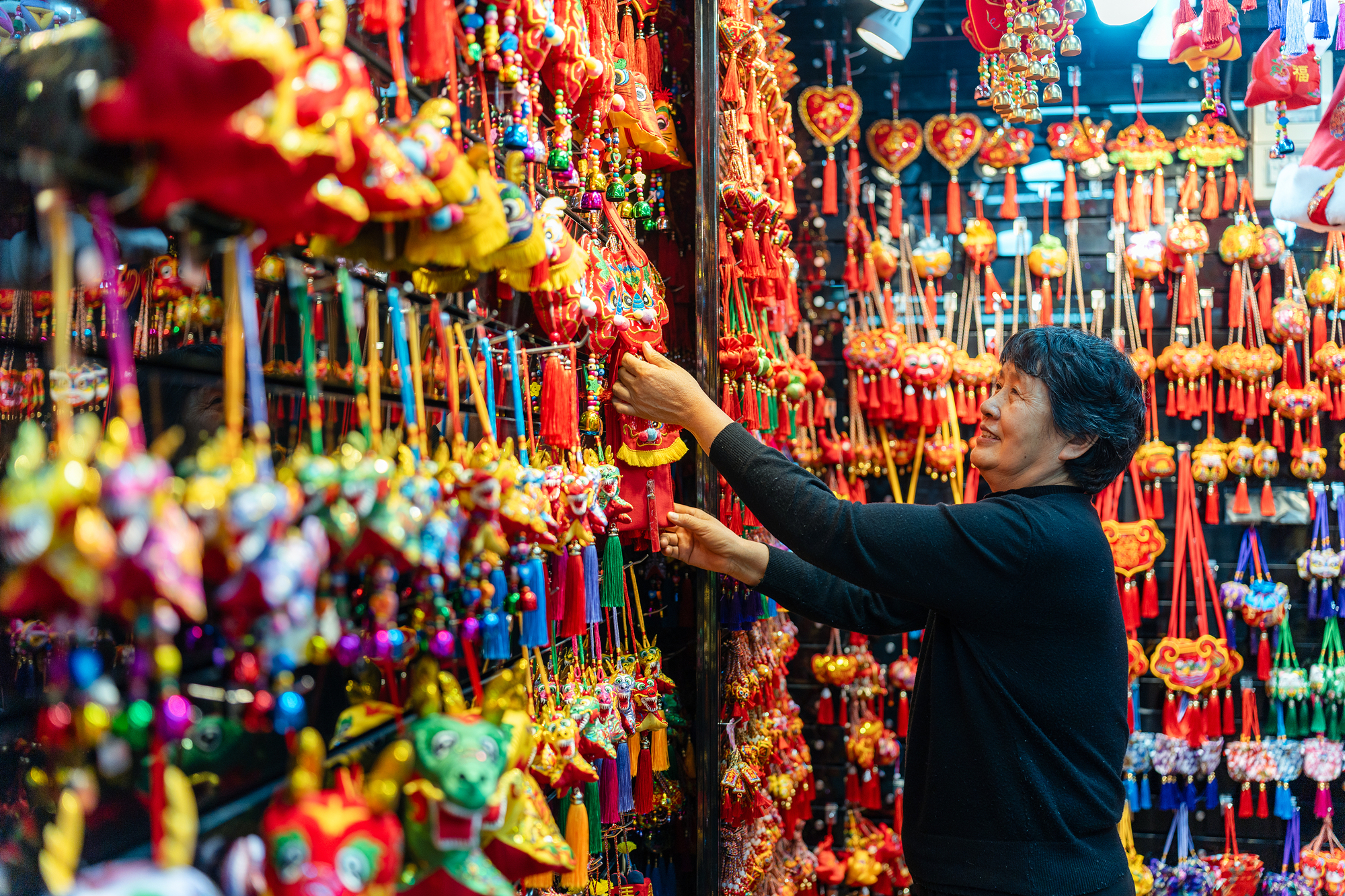 2023年12月11日，金華義烏國際商貿(mào)城，龍年喜慶用品掛滿攤位，顧客正在挑選中。