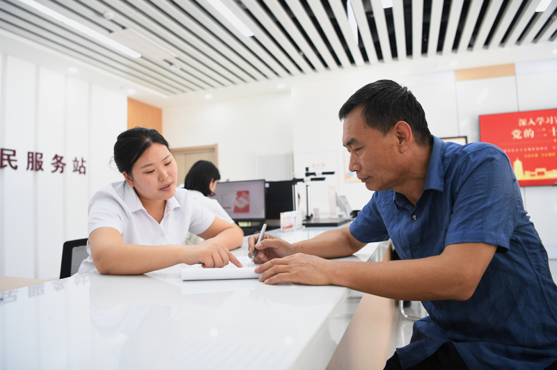 2023年5月23日，河北雄安新區(qū)容東片區(qū)南文營社區(qū)居民（右）在社區(qū)便民服務站辦理業(yè)務。